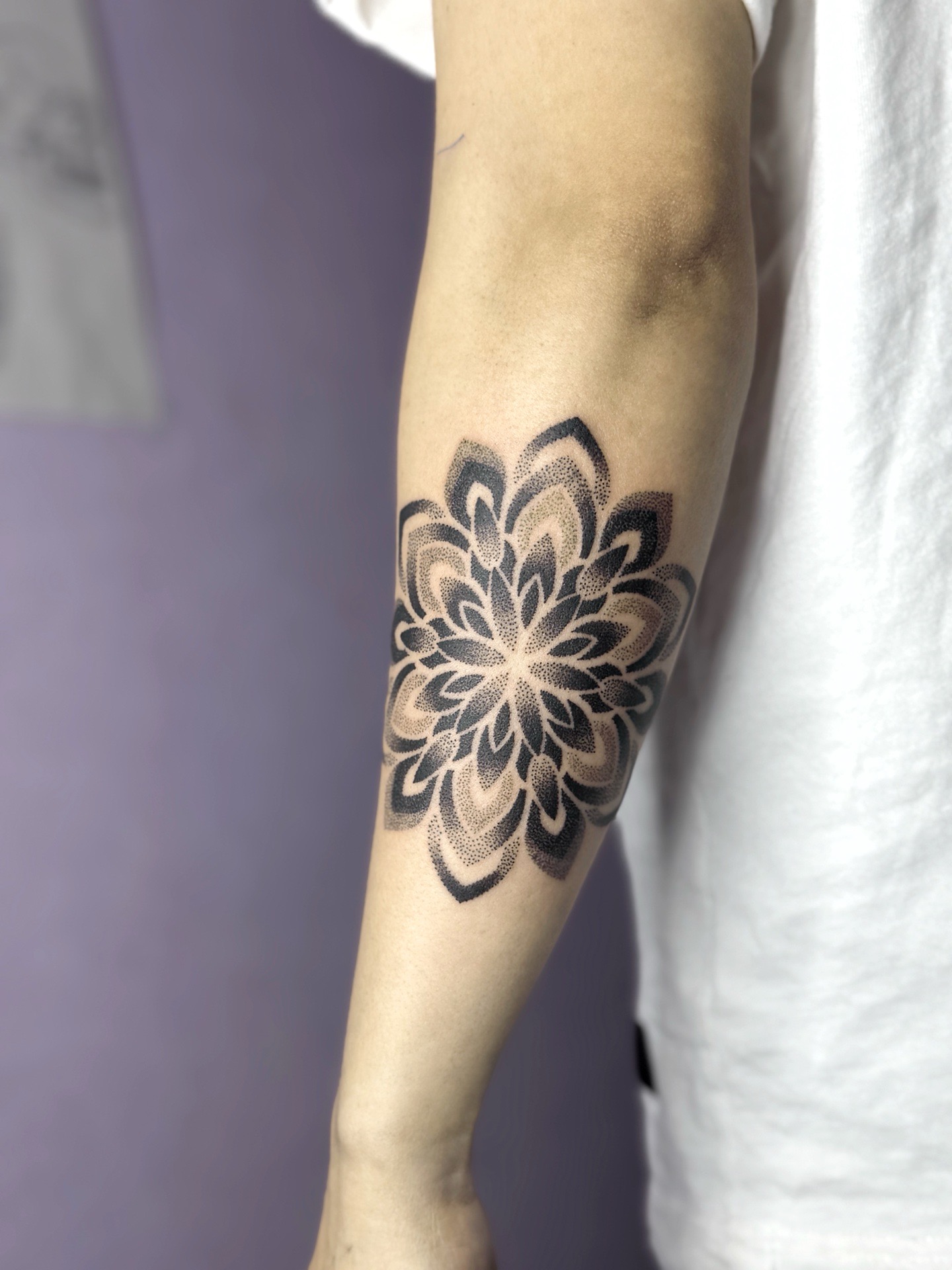 Tatouage en style dotwork représentant une composition mandala abstraite.