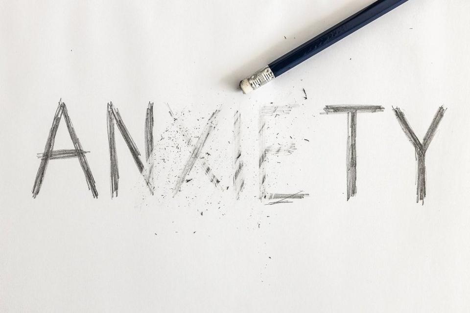 The wod anxiety written in pencil, with the pencil beside it, its eraser used to erase some of the letters.