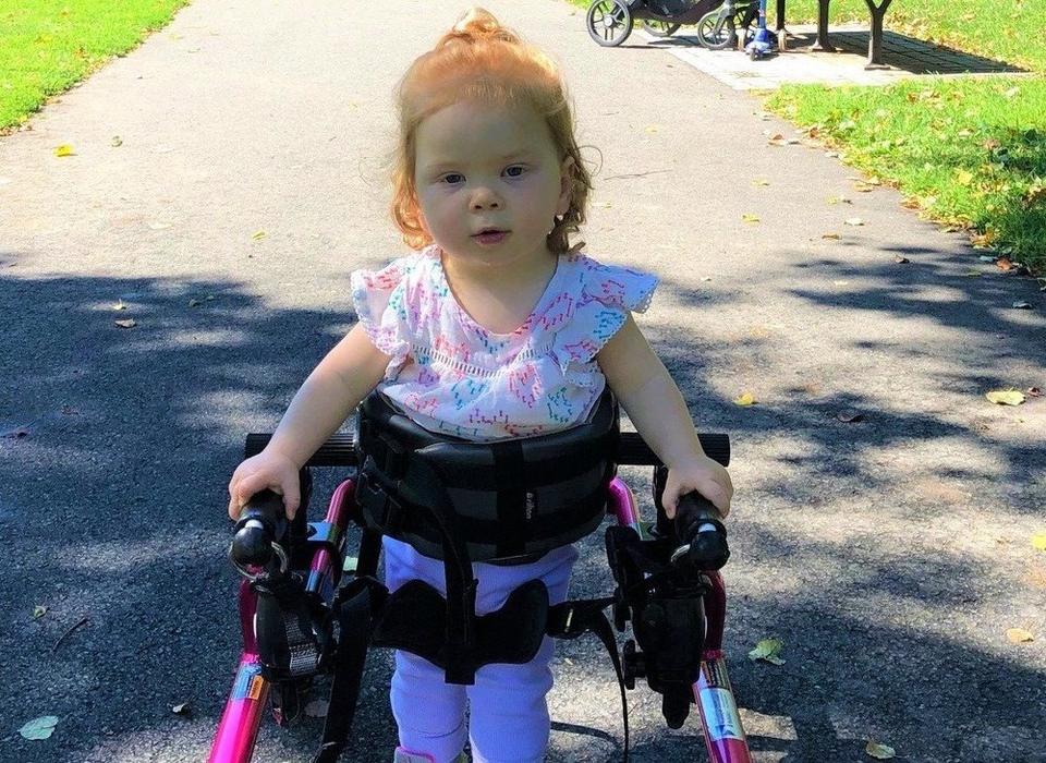 Avery outdoors in a gait trainer