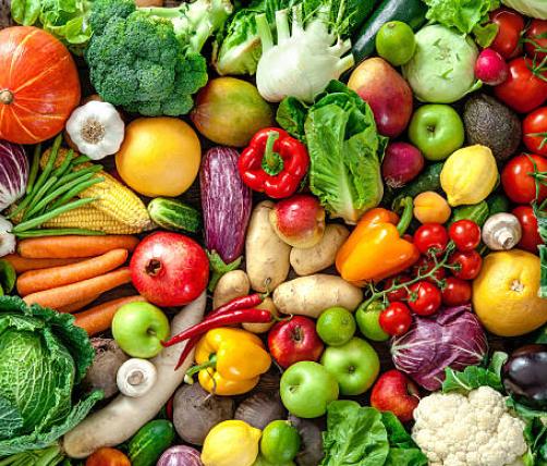 A variety of fruits and vegetables, such as peppers, apples, tomatoes, broccoli, eggplant, cauliflower, carrots, corn, garlic, etc