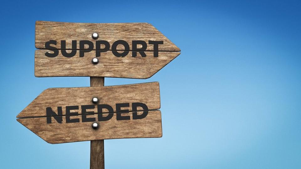 Two wooden sign posts shaped as arrows, with the words SUPPORT NEEDED in all caps