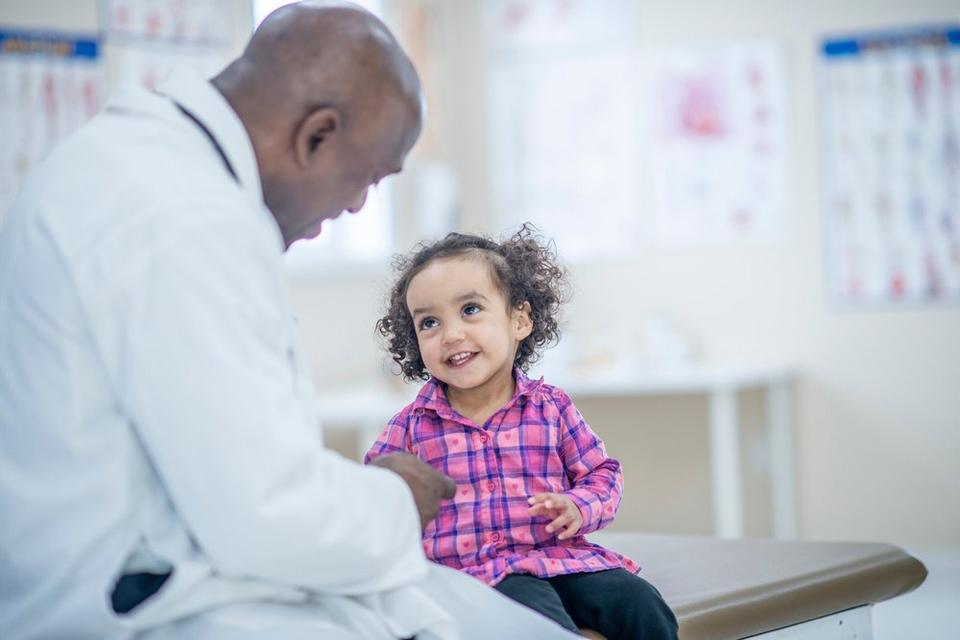 A docor and child, the patient, smile at one another.