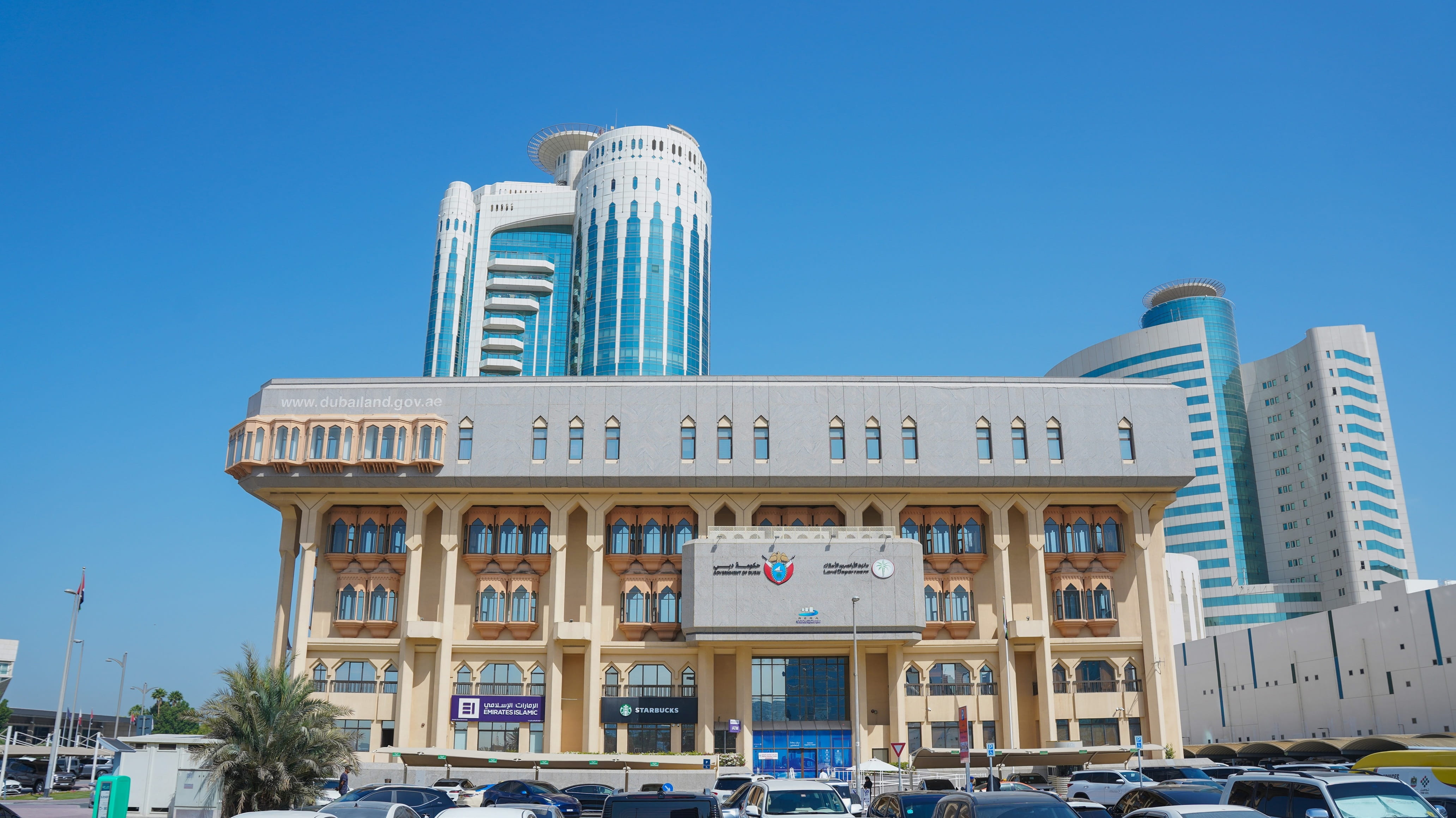 Official photograph of Dubai Land Department headquarters, Government of Dubai crest and Arabic–English DLD signage, with www.dubailand.gov.ae on the facade