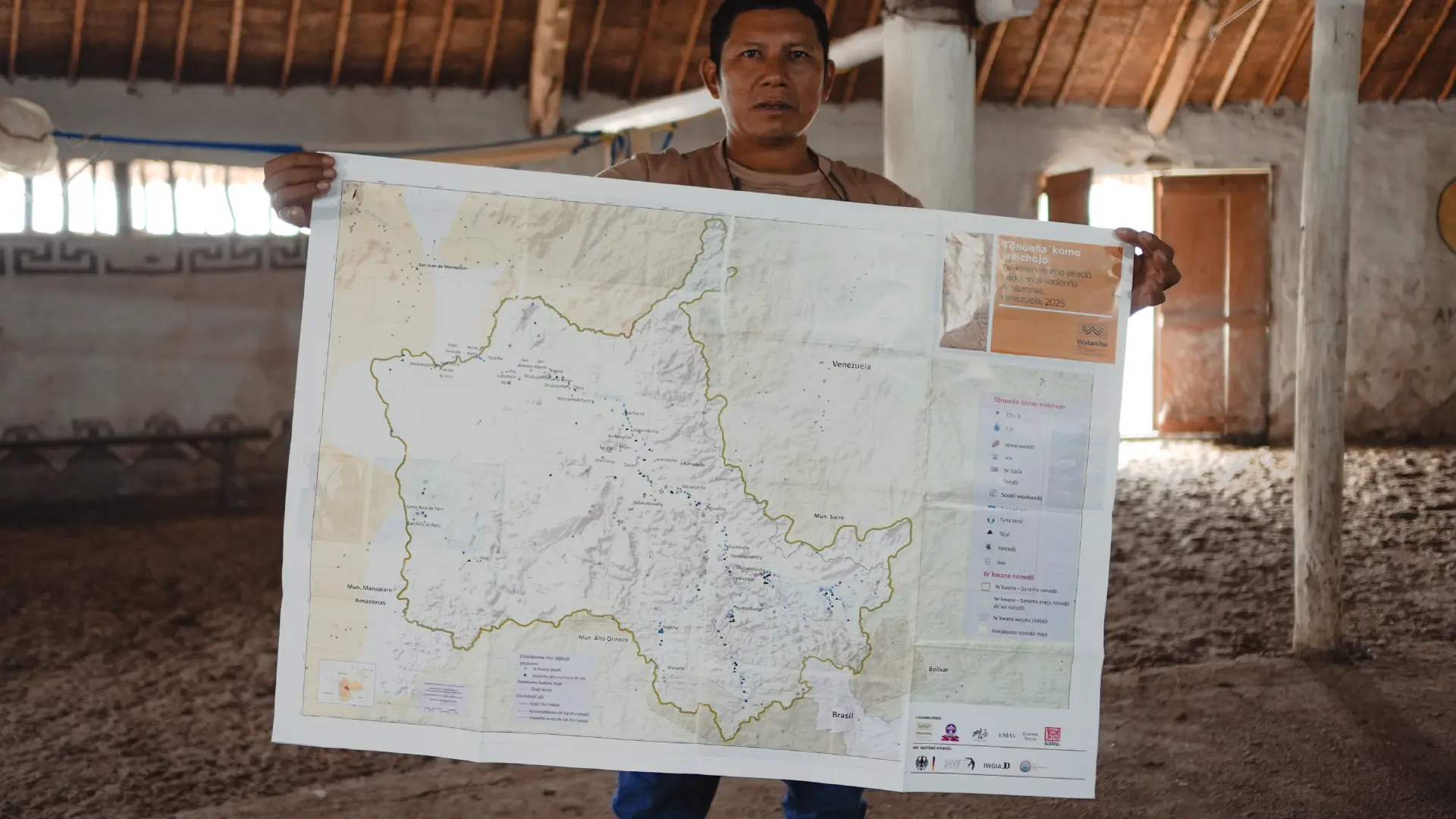 Hombre sostiene un mapa del territorio dentro de una churuata