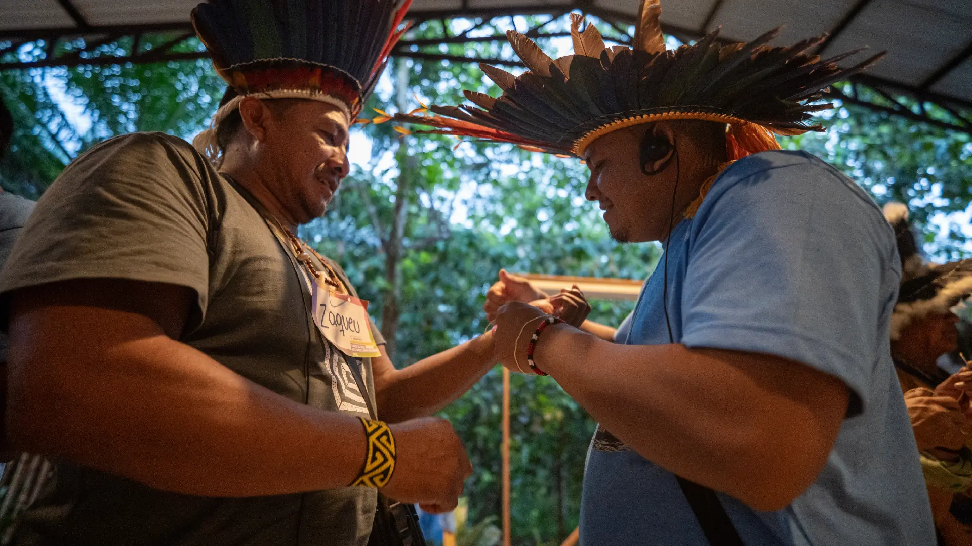 Dos líderes indígenas con tocados de plumas se saludan