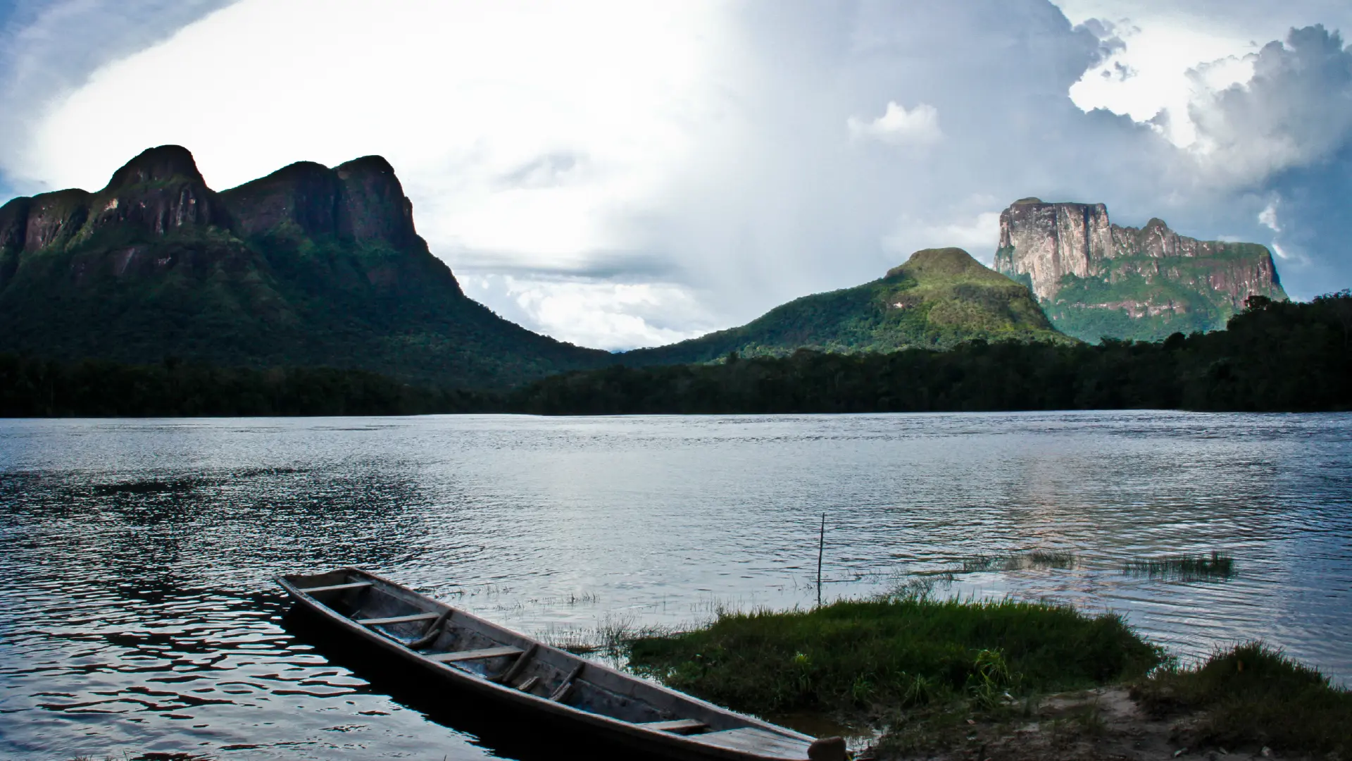 Canoa en la orilla de un río frente a tepuyes