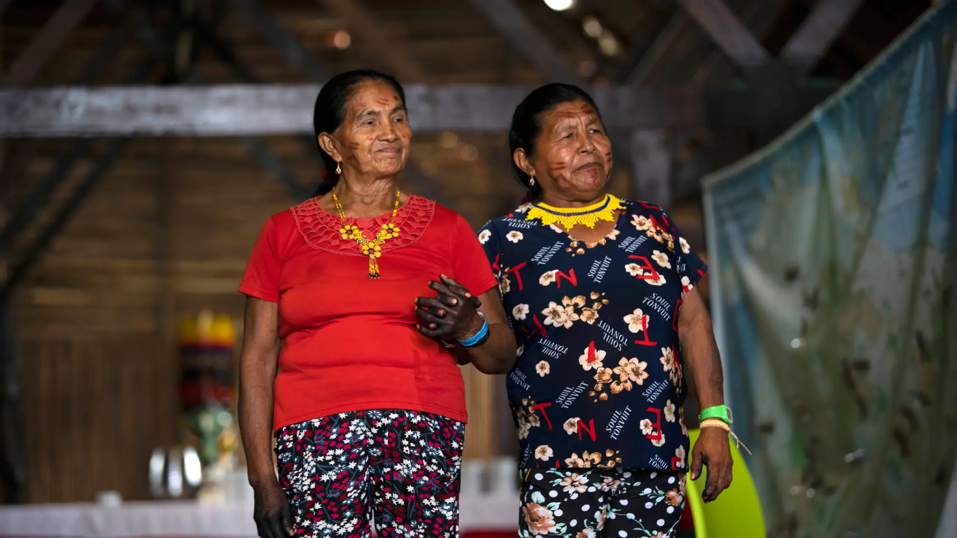 Dos mujeres indígenas caminan tomadas del brazo durante el encuentro