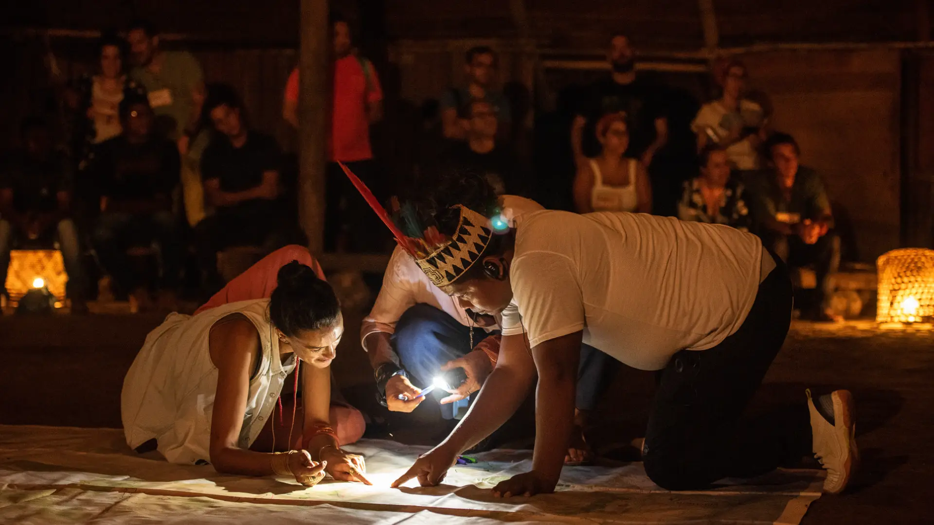 Participantes trazan un mapa en el suelo con linternas durante un encuentro nocturno