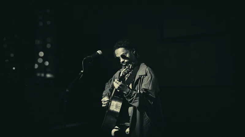 Black and white portrait of a guitarist looking down at his hands as he plays.