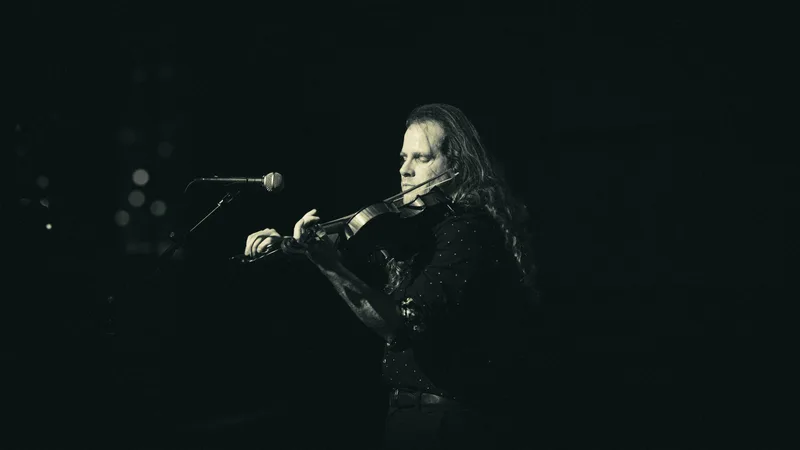 Black and white shot of a violinist mid-bow, head bent over the instrument.