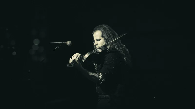 Black and white frame of a violinist playing, long hair falling forward.
