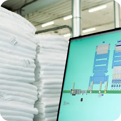 Immagine che rappresenta la biancheria piegata e pronta per la partenza accanto a un monitor che mostra una schermata del processo produttivo