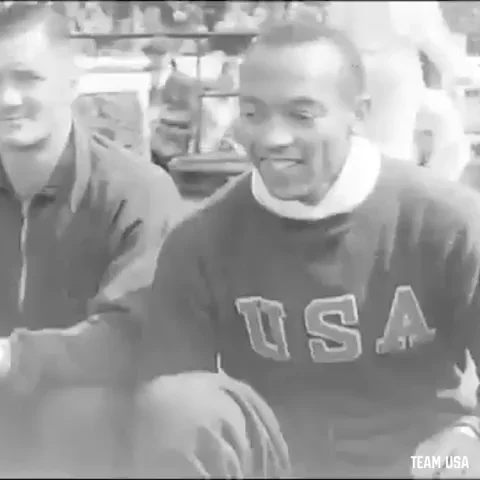 Jesse Owens brief film clip. He is smiling and wearing a USA sweatshirt.