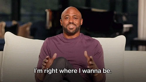 Wayne Brady sits on a comfortable couch and says, "I'm right where I wanna be."