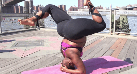 Woman practicing yoga on a pink mat and doing a headstand