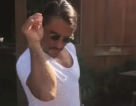 Chef Salt Bae dramatically sprinkling salt from a raised hand, in his signature pose.