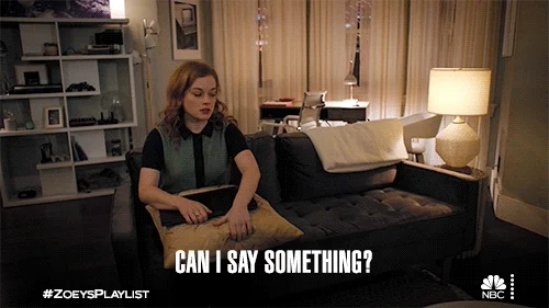 A woman in an apartment talking to her roommate. She asks, 'Can I say something?'