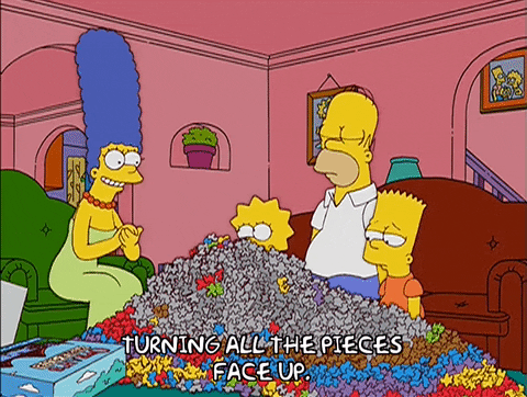 Marge Simpson is turning all the puzzle pieces facing up as her family watches
