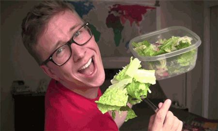 Man eating salad from a tupperware container making goofy faces