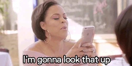 A woman raises a finger while looking at her phone and says, "I'm gonna look that up."