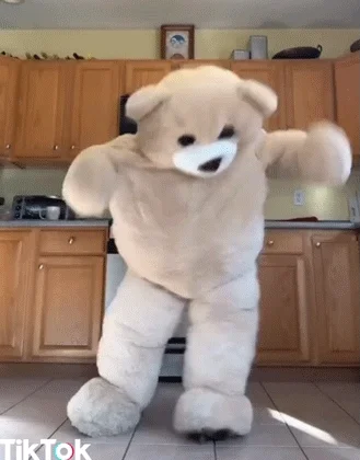 Person wearing white bear suit and dancing in kitchen 