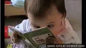 A kid is seen reading a picture book seriously.