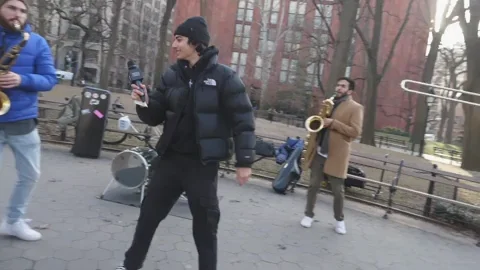 GIF showing two saxophone players and a singer jamming on the streets.