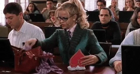 GIF: Elle Woods from movie Legally Blonde gets out fluffy pen during law class.