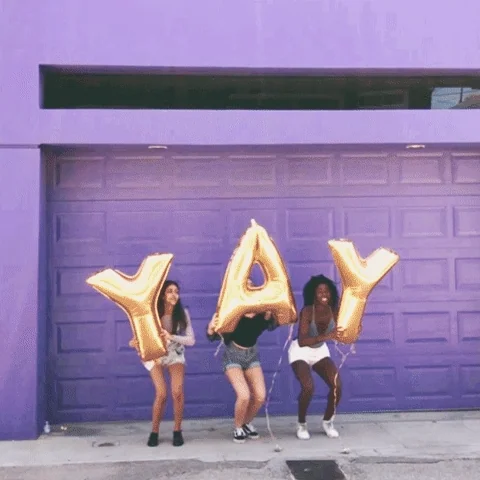 Three teen girls jumping in unison, each holding a giant balloon letter that spells Y A Y (yay).