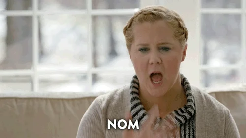 A woman licking her fingers and the word 'nom' appears 6 times