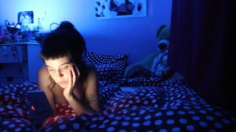 A woman scrolls on her phone while she's in bed.