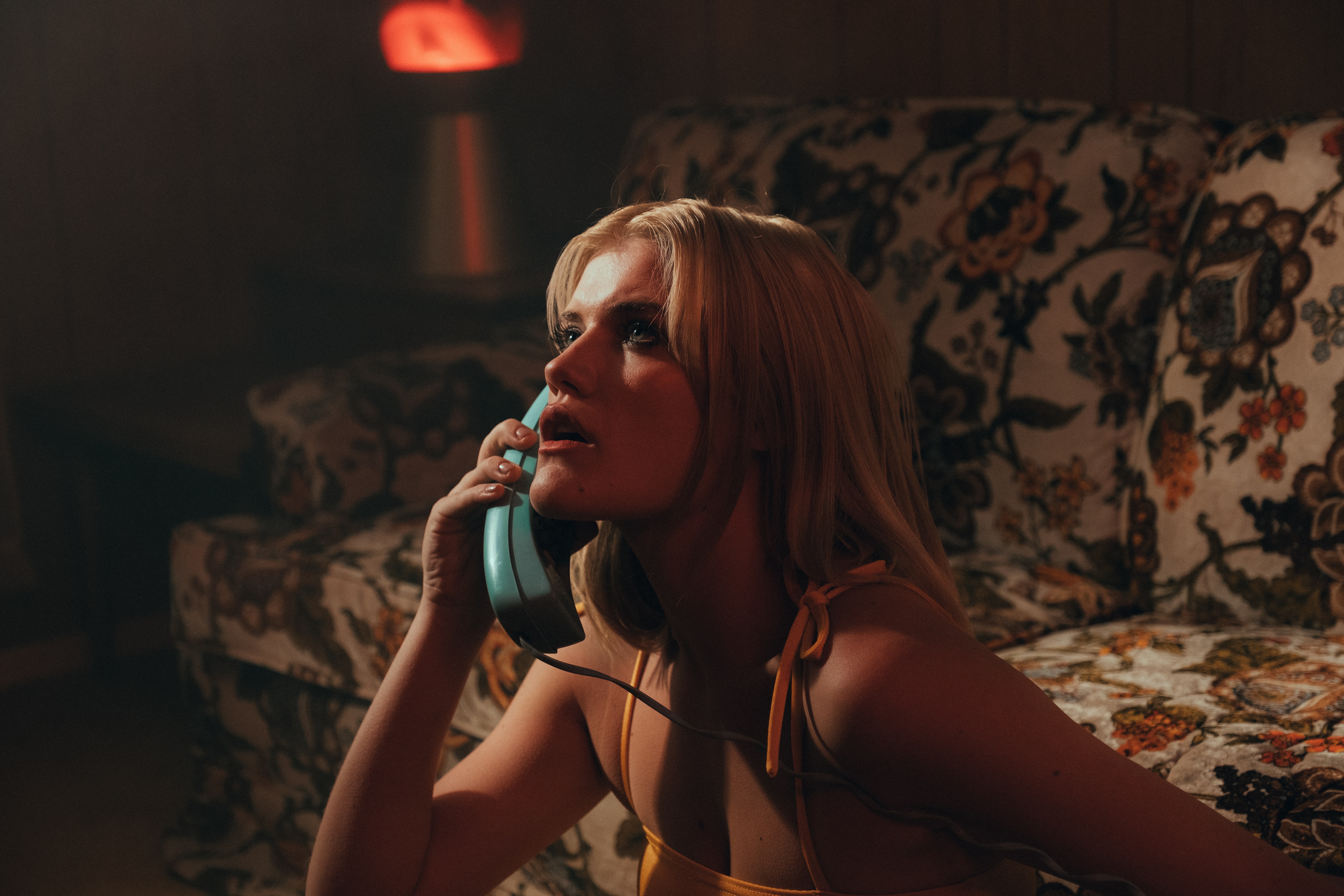 Photo by Jakob Owens on Unsplash. A woman sitting in a living room holding the telephone receiver to her ear.