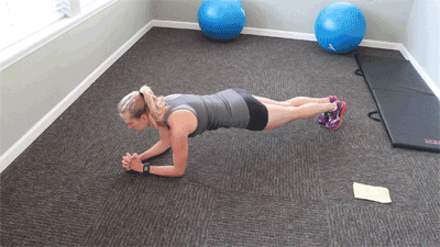 A woman planking on the floor of a home gym