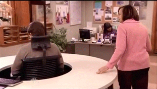 Woman trying to speak to a man at his office desk while he spins in his chair in a circle to avoid her.