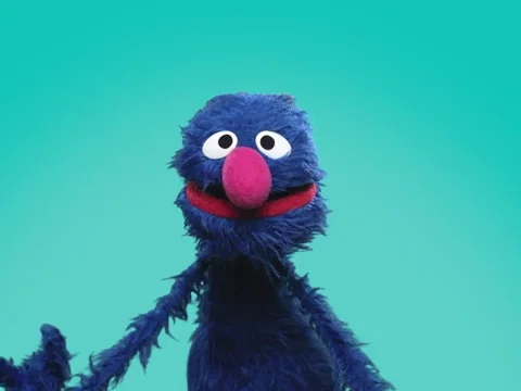 Grover from Sesame Street holds up a 
