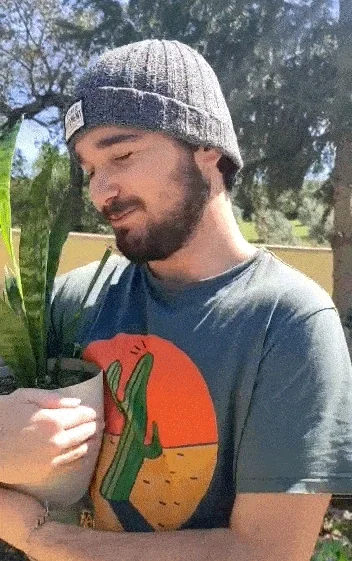 A man hugging a plant and kissing it.