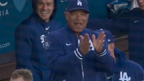 A baseball manager claps and raises his hands in excitement.