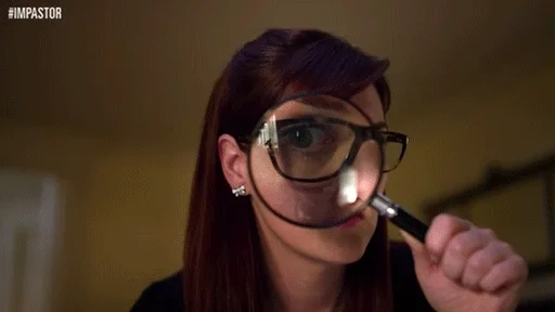 A woman holding up a magnifying glass to her eye, as if examining something curiously.