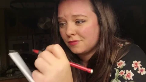 A person writing with a pencil and paper. The text reads: "Let me get that down."