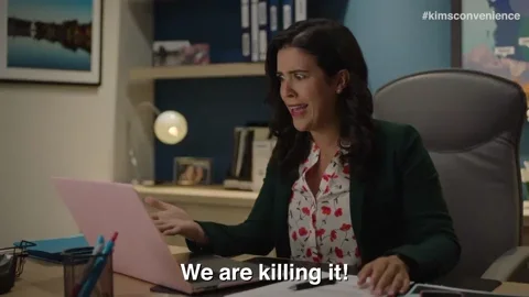 A woman sitting at her desk with her laptop open. She says, “We are killing it!”