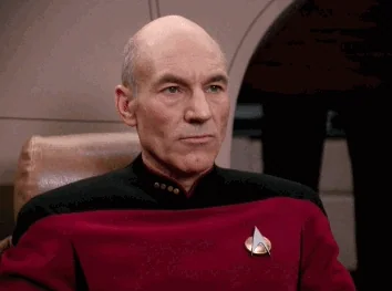 Patrick Stewart in Star Trek, dressed in red shirt, motioning, saying 
