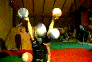 Person laying on their back juggling balls with their hands and feet