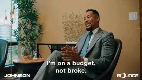 A man seated in a suit gesturing with his hands says: "I'm on a budget, not broke."