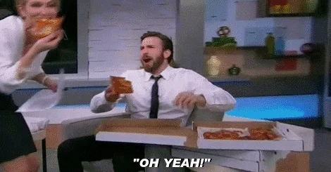A man eats pizza and says, "Oh yeah!" while pumping his fist.