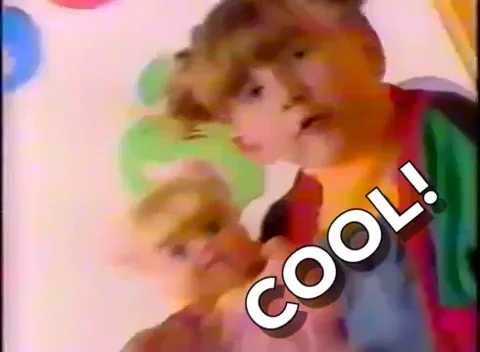 A girl holds a doll and says, "Cool!"