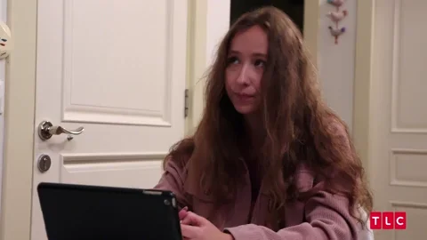 A young woman at computer gesturing to mean, 