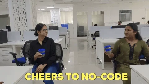 Two women in an office toasting with their coffee cups, with a caption that says, 