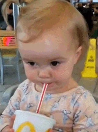 Toddler takes a sip from a cup with a straw and makes a sour face, tossing their head back.