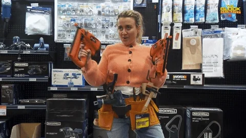A person in a hardware store holding tools and dancing.