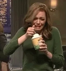 A woman wearing a green sweater crying while eating ice cream